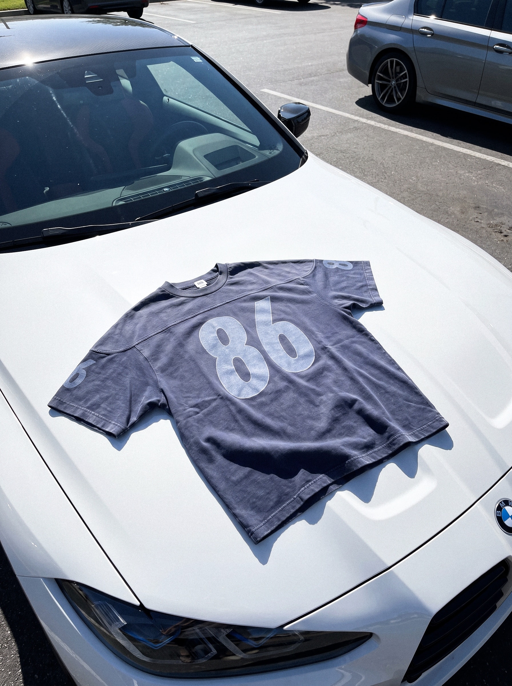 Graphic tee laid flat on the hood of a white car