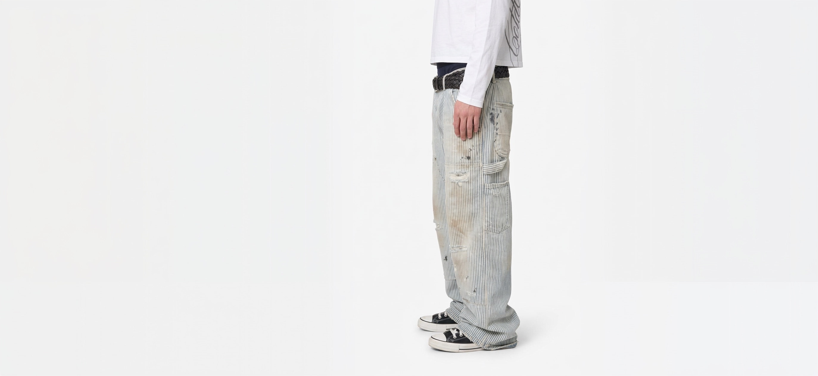 Side view of wide, washed carpenter jeans over canvas sneakers